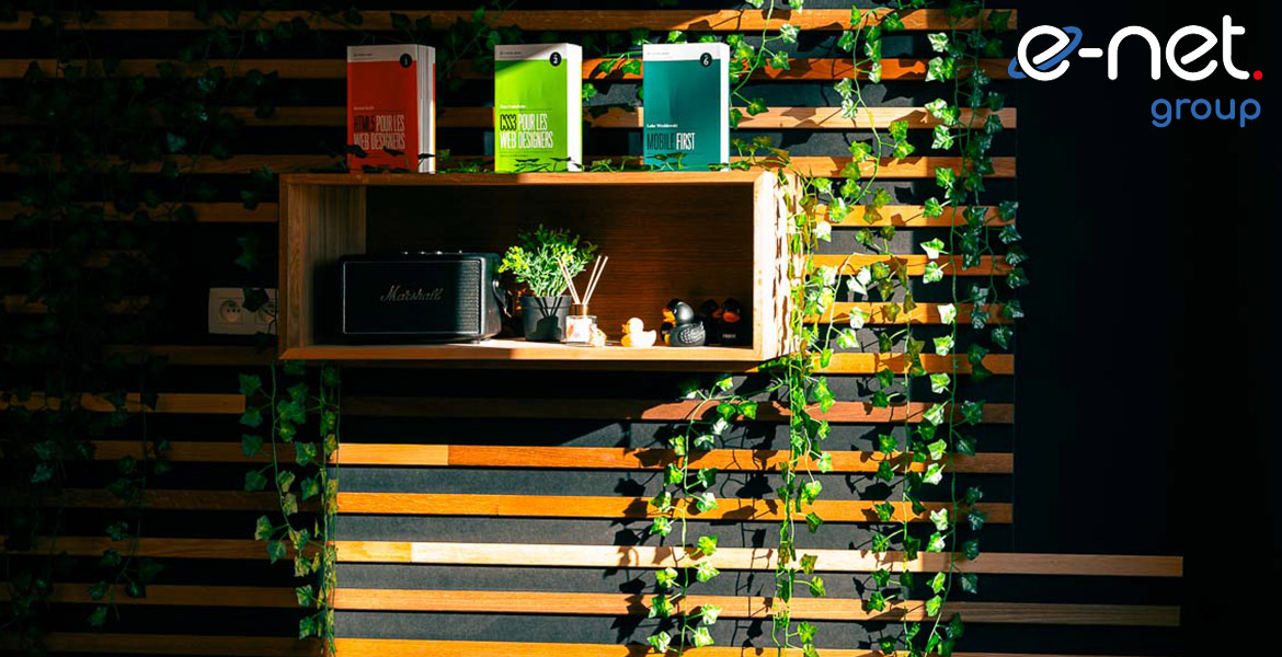 Étagère murale en bois avec des livres, une radio vintage, des plantes et des lianes vertes.