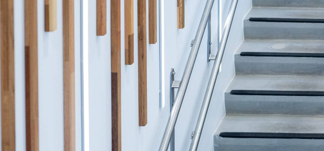 Escalier moderne dans les locaux e-net, avec rampe en métal et décoration murale en bois vertical.