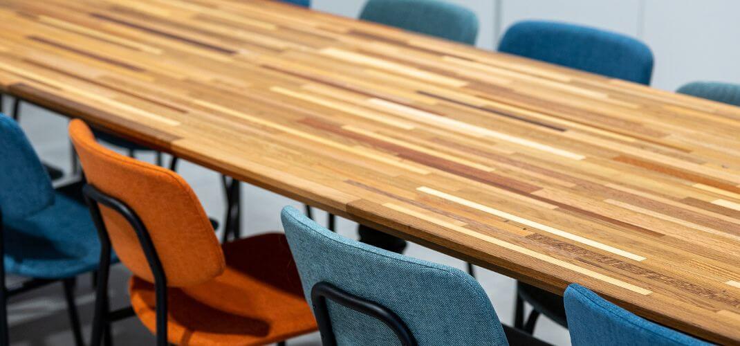 Table de réunion en bois multiton dans les locaux e-net, entourée de chaises colorées.